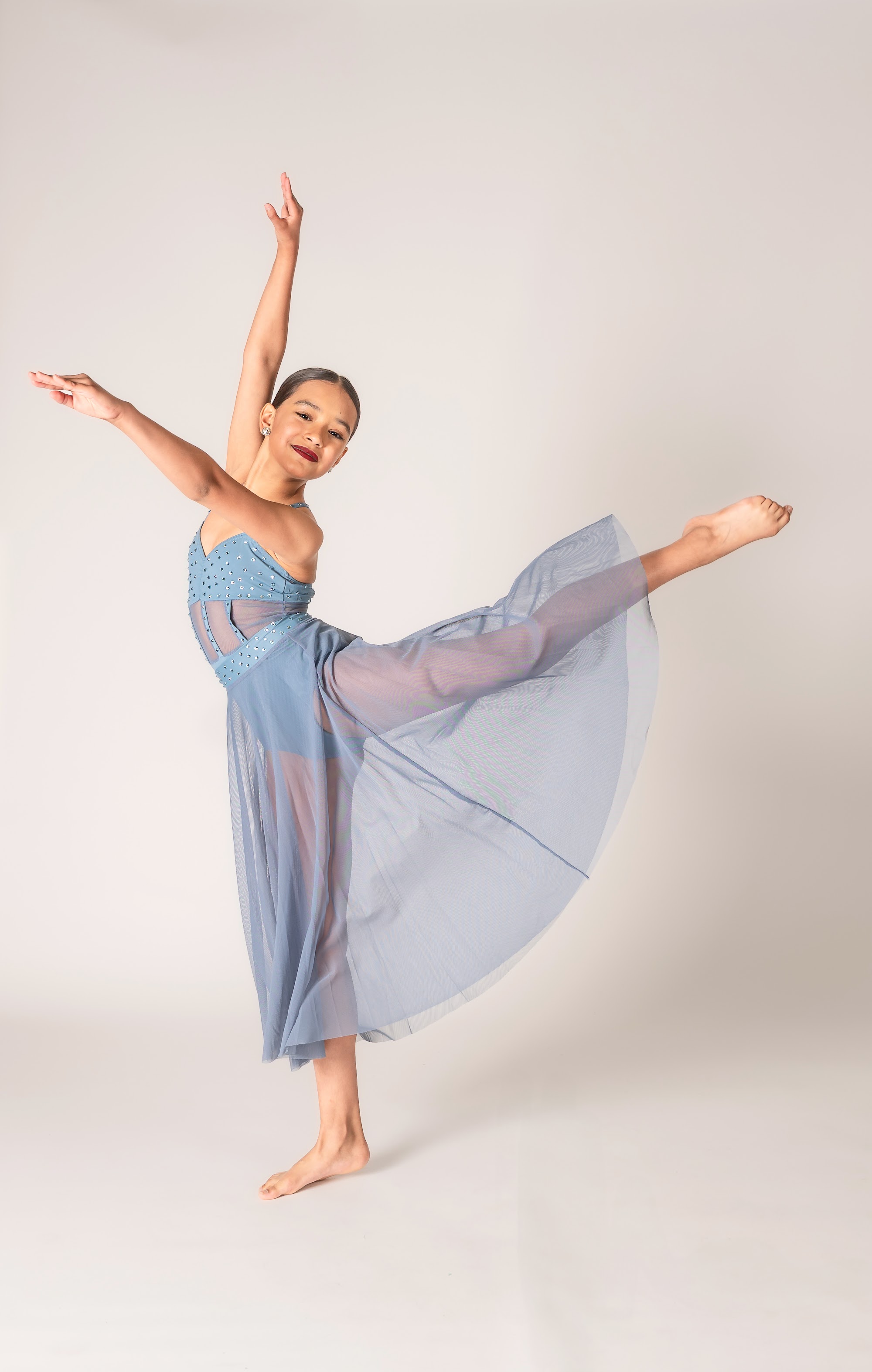 Upper level dancer in a long blue skirt in arabesque