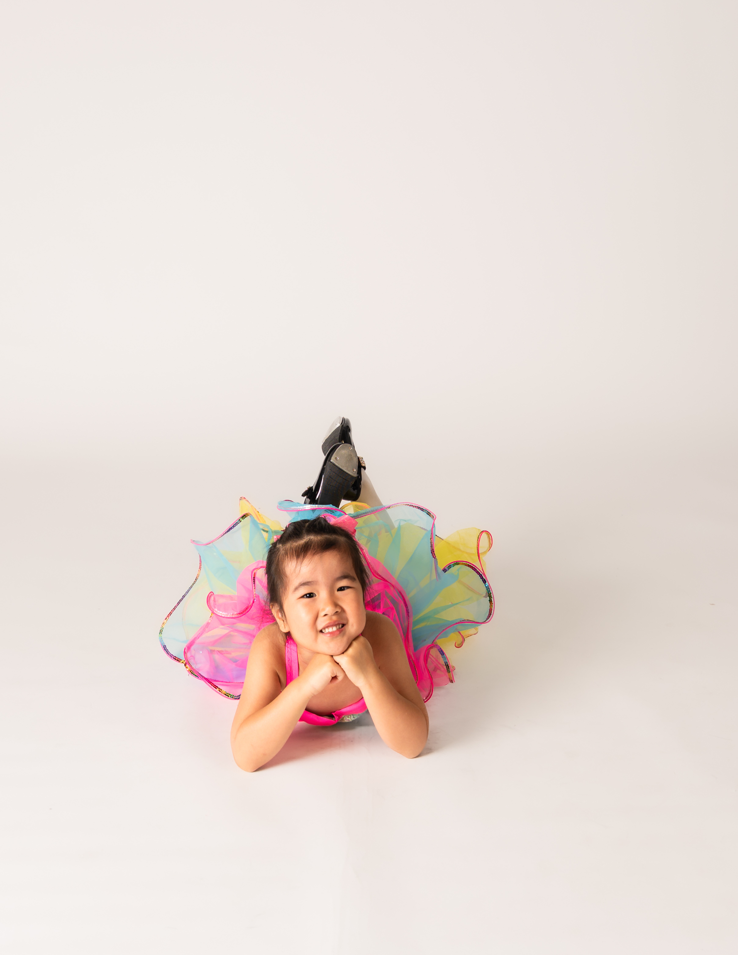 Young dancer in a rainbow tutu and tap shoes smiling on the studio floor
