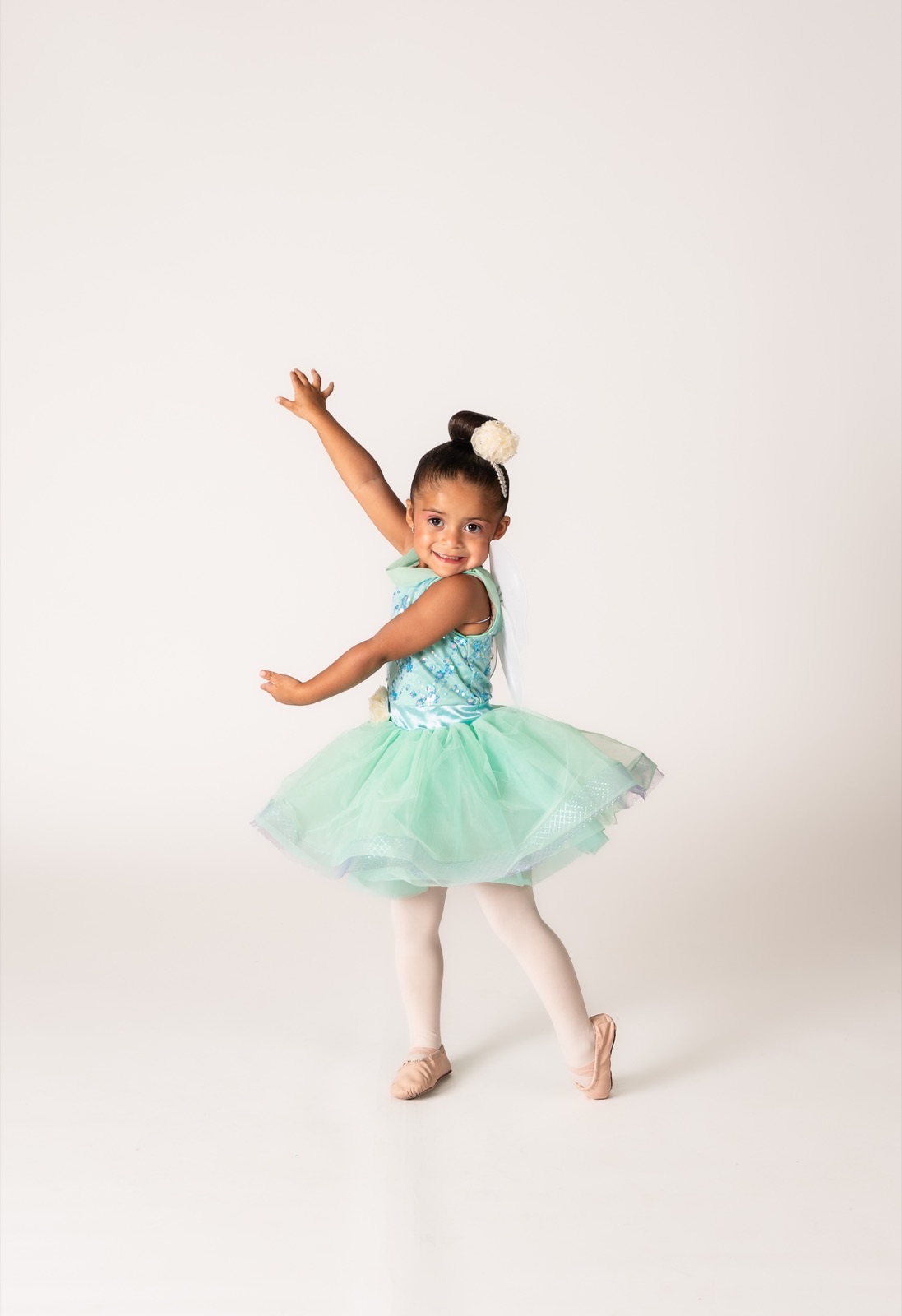 Two and three year old dancer in a mint tutu with arms open